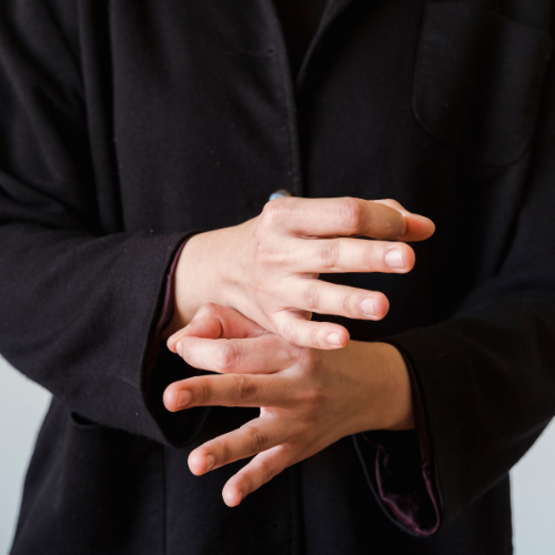 Person holding their hands while experiencing physical tension or discomfort