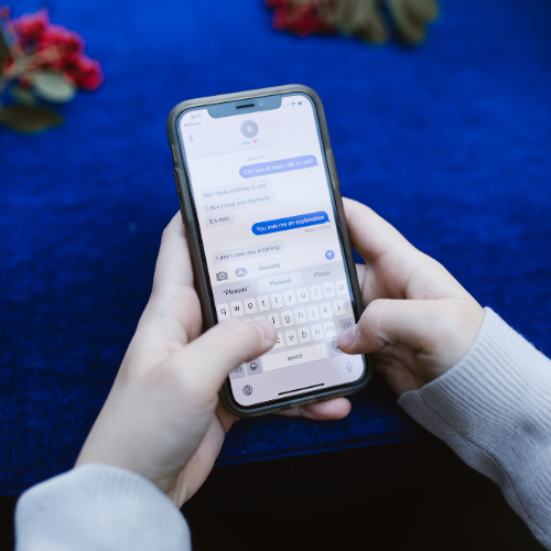 Person typing a message on their phone while considering whether to text someone after a breakup