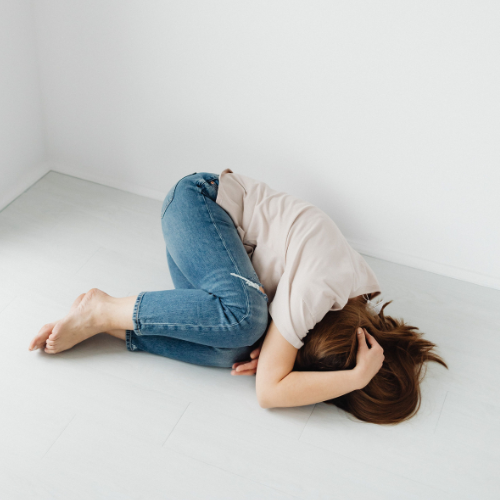Young woman curled up on the floor during a moment of emotional distress