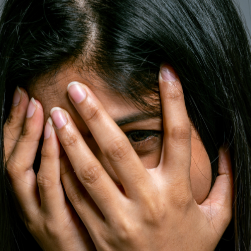 Young woman covering her face with her hands during a moment of anxiety