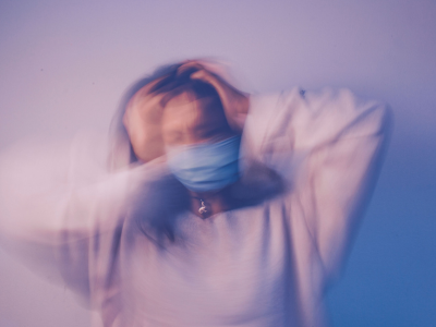 Blurred young woman holding her head, representing the fear and disorientation that can accompany an anxiety episode.